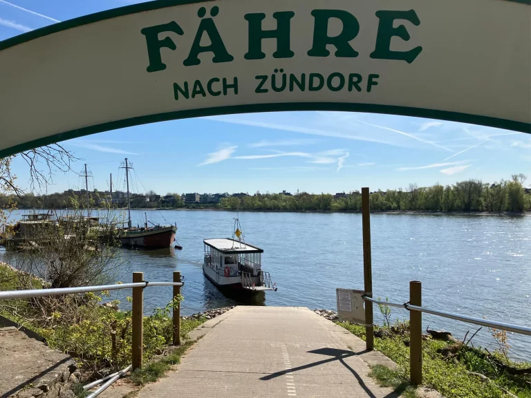 Foto des Fähranlegers in Köln-Weiß mit der kleinen Fähre nach Zündorf auf dem Rhein bei sonnigem Wetter.