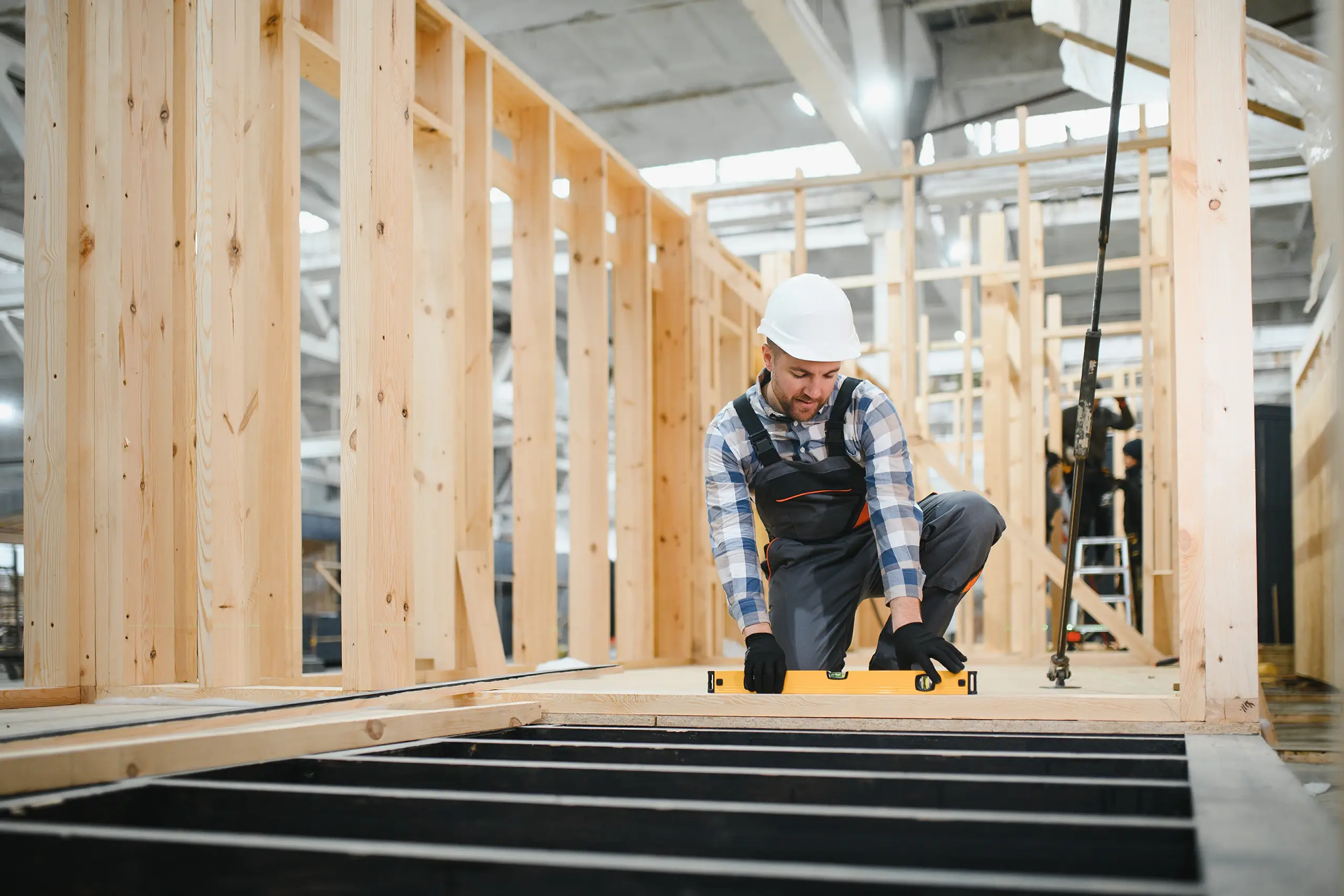 Porträt eines Zimmermanns, der in einem Holzlager seine Fachkenntnisse in der Modulbauindustrie präsentiert.
